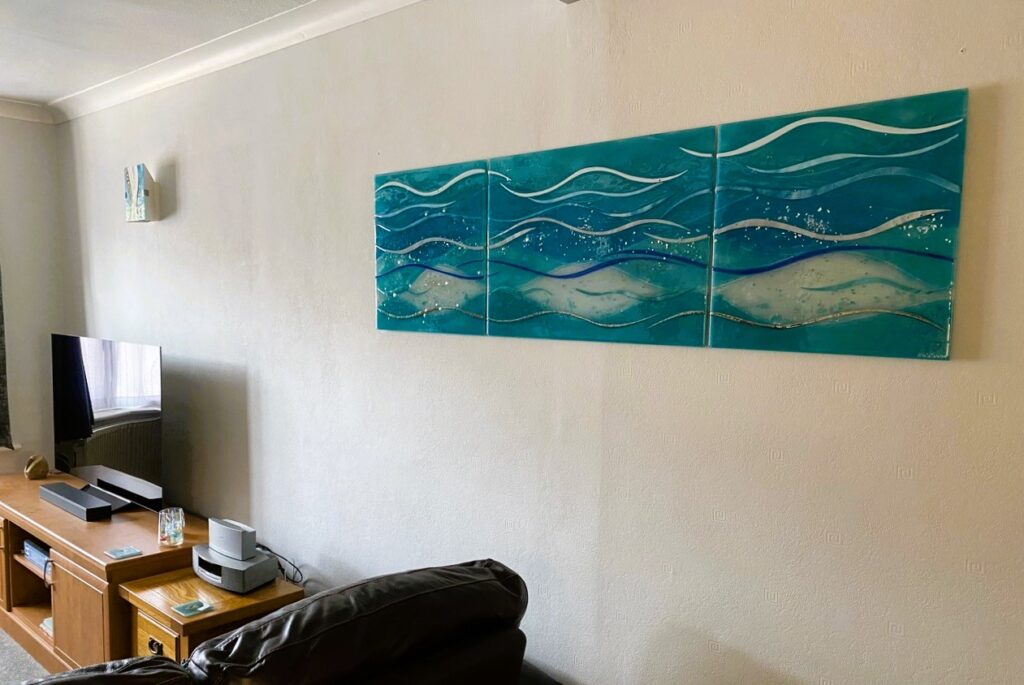 Bespoke fused glass wall art triptych in sea blues with a wave design and matching wall lights.