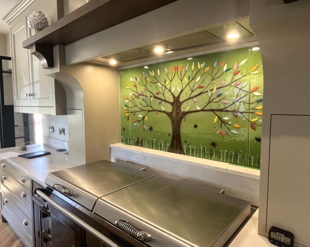 Bespoke fused glass Tree of Life splashback bringing colour to a stone coloured kitchen in Market Harborough.