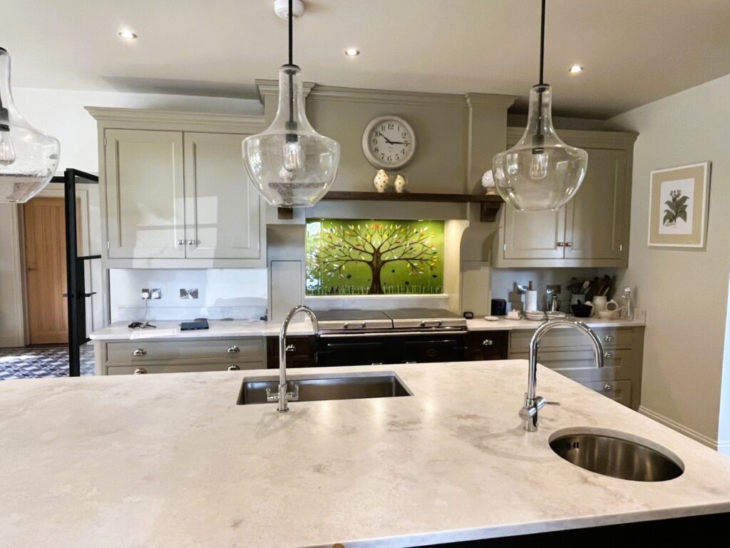 Green and multicoloured Tree of Life fused glass splashback installed in a stone coloured Market Harborough kitchen.