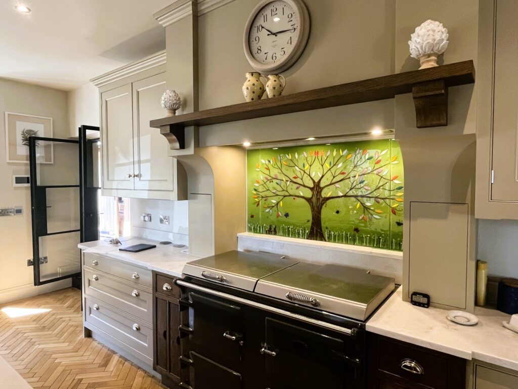 Bespoke green and multicoloured Tree of Life fused glass splashback in a stone coloured kitchen in Market Harborough.