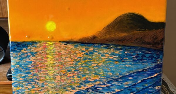 Handmade enamel powder glass panel showing an orange sunset over blue water and coastal hills, measuring 60 x 88 cm.