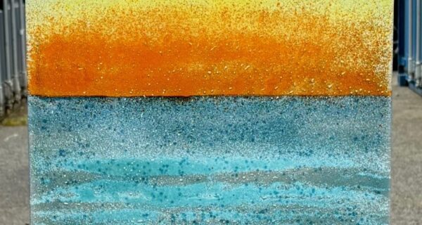 Transparent fused glass panel showing a sunset beach scene in red, orange, yellow and blue, measuring 181.5 x 48 cm.
